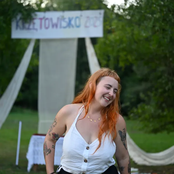 Festiwal Krzętowisko — uśmiechnięta uczestniczka przed festiwalowym banerem